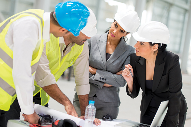 two construction workers and two women in professional attire meeting over plans